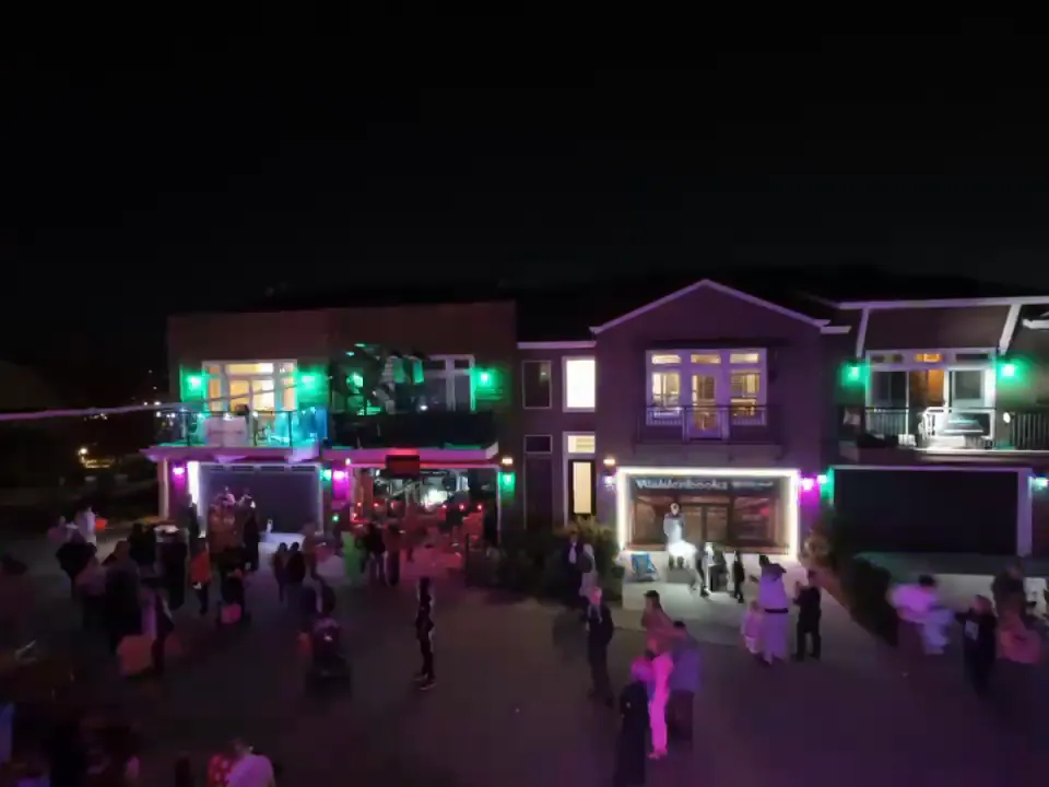 An aerial view of the court at night, lit green and white, with the crowd spread across the street.