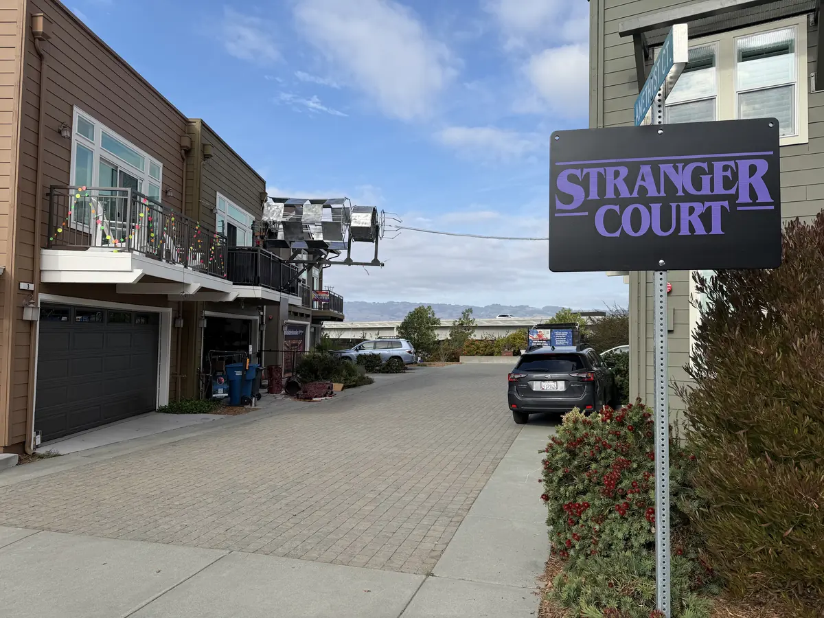 The Stranger Court street sign in daylight, with the rig already hung on a balcony down the street.