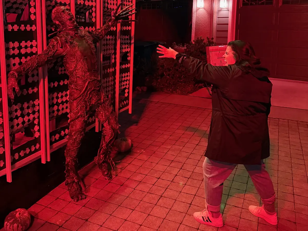 A life-size Vecna figure against a red-lit wall of panels, with a visitor acting like they are being pulled toward it.